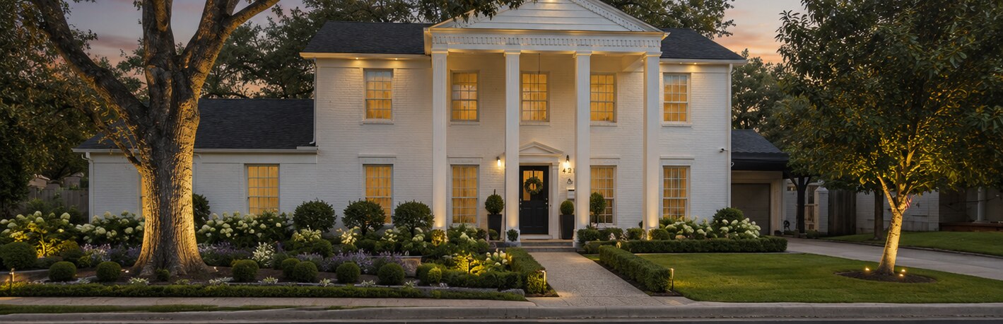 Same colonial home after a full repaint with manicured landscaping and warm dusk lighting