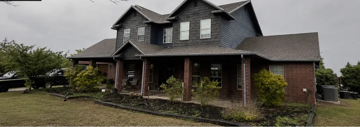 Two-story brick and siding home on a flat, overcast day before the project
